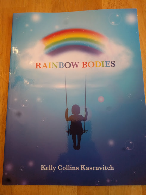 the cover of the book, "Rainbow Bodies" - there is a blue gradient background with light orbs. At the top there is a rainbow with clouds at the ends, and the title in different colored letters in the clouds. Hanging from the clouds is the silhouette of a person on a swing.